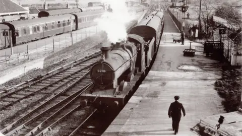 North Sedgemoor Local History Group A steam train is coming into Burnham's old station. The photo is black and white.