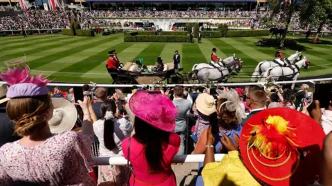 Reuters Crowds watch on in colourful hats and headpieces as the royal procession arrives at Ascot.