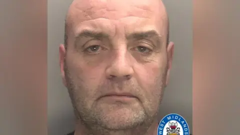 A police mugshot shows a man with a shaved head and stubble. There is a West Midlands Police logo in the bottom right of the image.