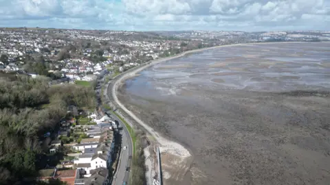 An aerial view of Swanasi, with water on the right and many houses in Swansi on the left 