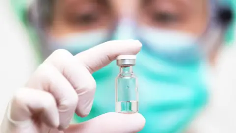 A doctor holds up a vial of the drug in his gloved hand