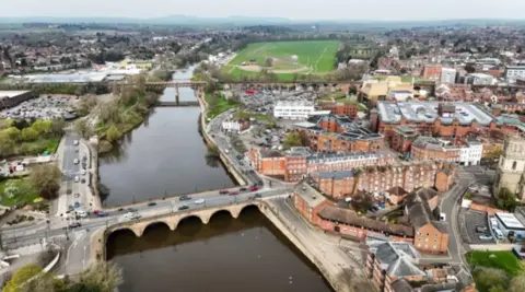 A aerial view of a city with a large bridge crossing a wide river in the centre