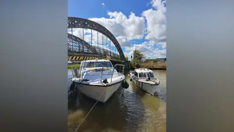 HM Coastguard Gorleston The boat wedged under the bridge and a smaller white boat to the side of it, with someone standing up.