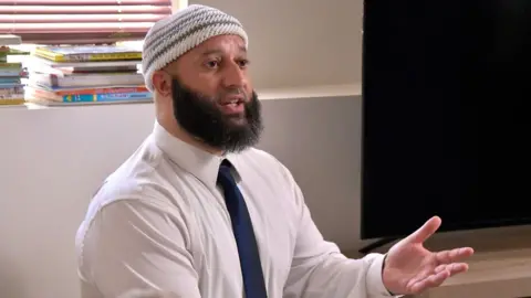 Getty Images Adnan Syed gestures while speaking in front of a window in his home