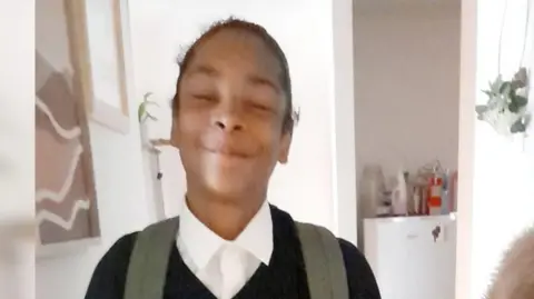 Mary Bokassa Kelyan Bokassa, a black boy in school uniform, chest upwards 