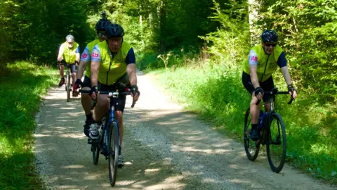 Group of cyclists on a country lane, surrounded by trees