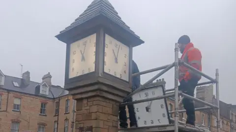 Redcar and Cleveland Borough Council A worker in an orange hi-vis jacket is stood on the scaffolding next to the clocktower with the restored clock ready to be installed.