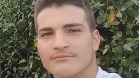 Cleveland Police Armando Marky has short brown hair and brown eyes. He is wearing a white t-shirt. 