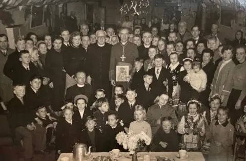 Ilford Park A period photo of a priest surrounded by parents and children at the park. 