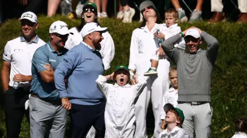 Shane Lowry, Rory McIlroy and their families react to Frankie Fleetwood hitting his ball in the water on the ninth hole of Augusta National's par three course