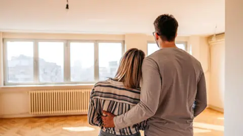 A couple looking across an empty room in a new house