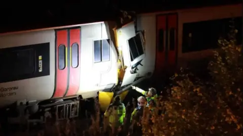 Dan Jones Train carriage with damage to window and emergency services at the scene after dark