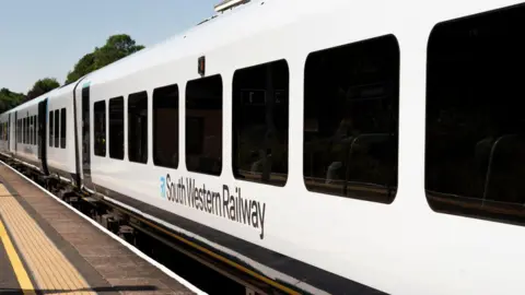 A white train. It has black writing on the side reading "South Western Railway".