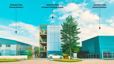 Mandy Young Adrenaline Alley Drawing of grey and blue industrial building to the left and a blue building to the right. The side of the glass and steel hotel with four stories is seen in the centre, with a tall tree in the foreground. Yellow-framed accommodation units are visible in the building. A white car is parked outside.