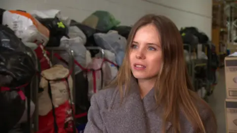 Kateryna Seranova standing in front of bags of donations