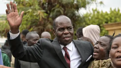 Gilbert Deya (C) in a black suit and a red tie celebrates outside a court with his followers in Nairobi on July 17, 2023