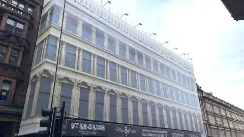 A facade showing Greek-style arches on the front of a tall building.