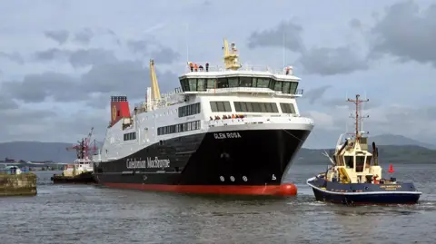 Christopher Brindle A large black, white and red ferry, leaving a dry dock, with tugs at the bow and stern