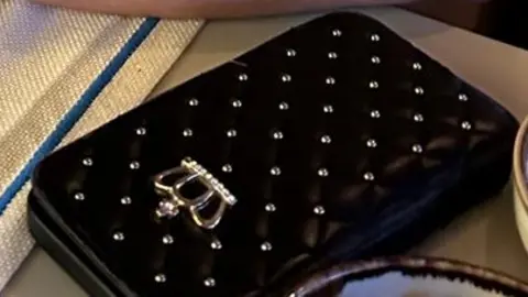 Suffolk Police A black wallet style quilted case with gold crown and stud detail, for an Apple iPhone