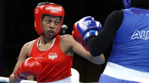 Getty Images Sameenah Toussaint of Team England competes with Tina Rahimi of Team Australia during the Women’s Over 54kg-57kg (Featherweight) Quarter-Final 4 fight on day seven of the Birmingham 2022 Commonwealth Games. Sameenah wears a red kit, head guard and gloves and is sparring with Tina