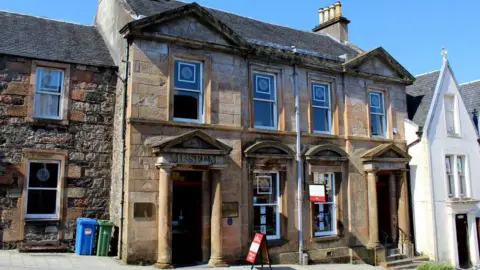 Chris Heaton/Geograph A picture of the West Highland Museum, which is two storey Victorian building. It has large windows and Doric portico doorways.