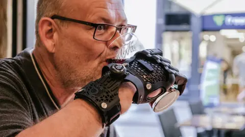 PA Michael Altheim pictured using the Hero Gauntlet to drink a large glass of Coca-Cola. 