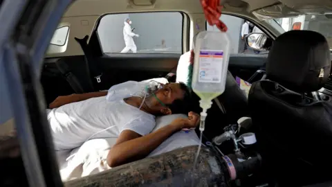 Reuters A patient with breathing problems lies inside a car while waiting to enter a Covid hospital for treatment in Ahmedabad, India