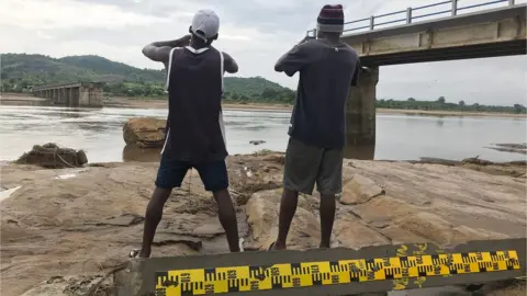 EPA Two men take pictures of a destroyed bridge after Tropical Storm Ana hit the district of Tete, Mozambique, 27 January 2022