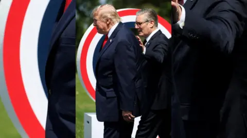 Starmer puts his hand on Trump's back as they walk side by side.