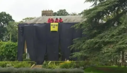 PA Media The activists unfurled banners when they climbed on the roof of the former prime minister's home