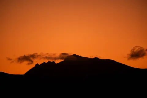 Ross Manson The sleeping warrior of Arran - hills which resemble a sleeping human - being bathed in orange light from a sunset or sunrise