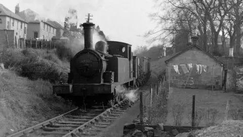 A black and white image showing a daily goods train on the Monkland & Kirkintilloch line travelling between Whitegates and Woodilee, 7 March 1960.
