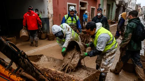 Getty Images Volunteers and emergency services are working to clean the streets in Paiporta, in Spain, two weeks after the region was hit by deadly floods