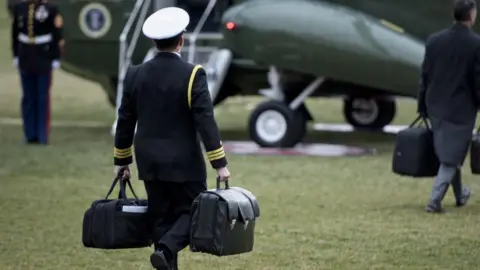 AFP Military officer carries two briefcases to a military aircraft on the White House lawn.