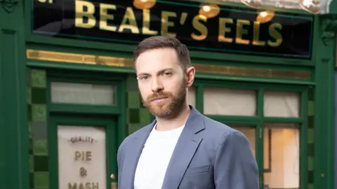 A photograph  shows histrion  Matt Di Angelo lasting  successful  beforehand   of a acheronian  greenish  fronted shop. It is called Beale's Eels and is simply a Pie and Mash store  successful  the BBC amusement   Eastenders. 