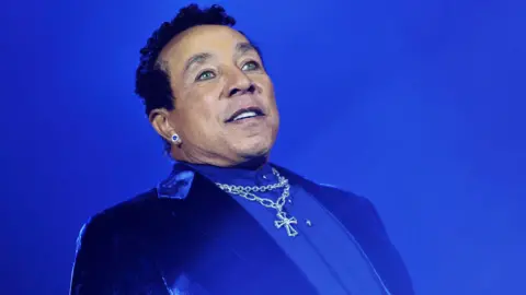Smokey Robinson, dressed in a blue suit, performs on stage in Hyde Park, 2013