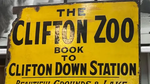 Yellow sign saying "The Clifton Zoo" and advertising how to book.