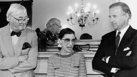 The Washington Post/Getty Images Supreme Court nominee Ruth Bader Ginsburg answering reporter's questions during courtesy call to Senator Joe Biden's office. She's standing with Sens. Biden and Daniel Patrick Moynihan 15 June, 1993