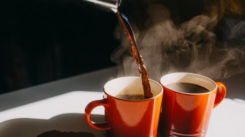 Coffee being poured into two mugs
