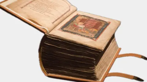 The Codex Amiatinus has been opened onto one of it's first pages. It is is a very thick book with two straps coming off the back cover which are used to fasten it shut.