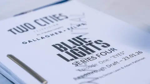 MILK A white block of paper has the words 'Blue Lights' in its' centre, in black font. Below it, it reads 'Series Four- Episode one: Eyes.'