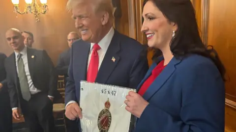 NI Executive/PA Media Deputy Minister Emma Little Pengely is holding a personalized flag from the Royal Port Rush Golf Club along with President Donald Trump at the U.S. Capitol in Washington, DC. 