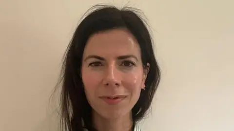 Name for Oxevision cameras to be banned in psychological well being sufferers' bedrooms A woman - Dr Jay Watts - looking directly into the camera. You can only see her head and neck. She has dark brown hair and brown eyes.