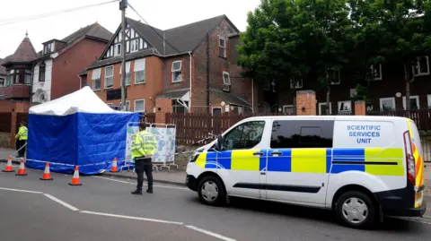 Police officers in Dunstable Road with a forensics tent