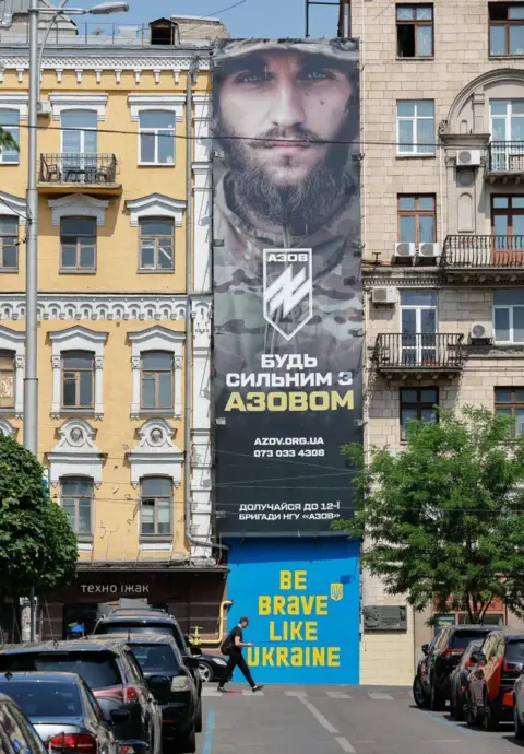  EPA-EFE/REX/Shutterstock People walk past a recruiting poster of the Azov brigade in Kyiv, Ukraine. Photo: May 2024