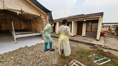 Mercy Juma/BBC Setting up a temporary treatment tent