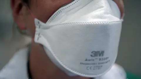 Close up of the face of a female medical worker wearing a white face mask