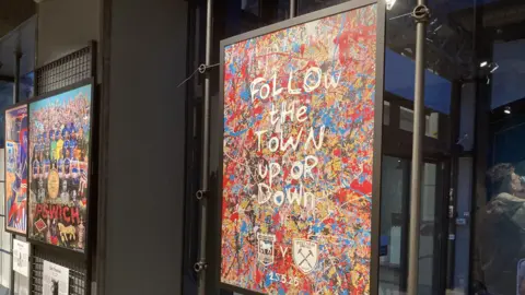 A work of art by Ed Sheeran showing paint splashes in lots of colours with football logos on it. 