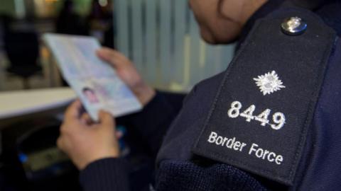 A UK Border Force official checks a passport