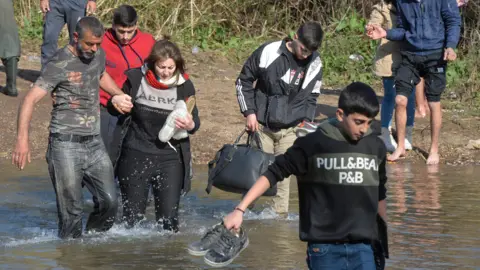 Reuters Alawite Syrians, who fled the violence in western Syria, cross the Nahr el-Kabir river in Akkar, Lebanon (11 March 2025)